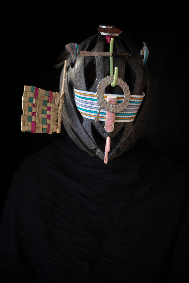 A dark mask with some bright highlights emerges from a black background.
