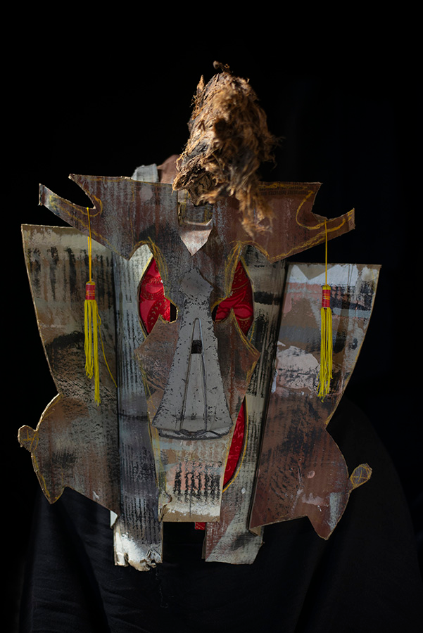 An ominous looking mask in grey and brown on a black background.