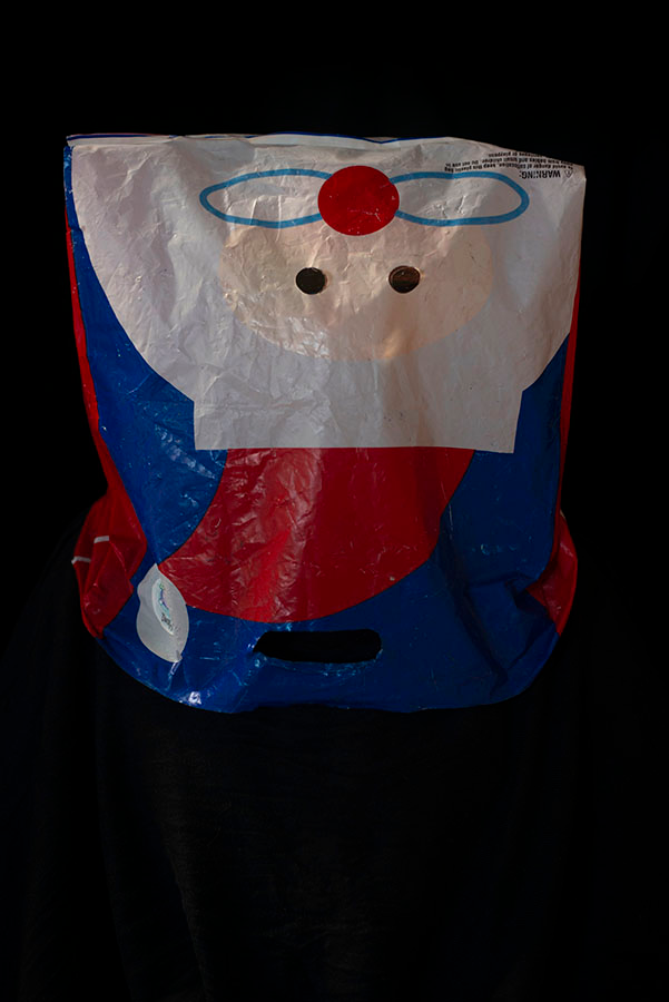 A mask consisting of an upside down plastic shopping bag with a cartoon image of Santa Claus
