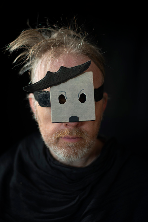 A male head wearing a small black and white mask.