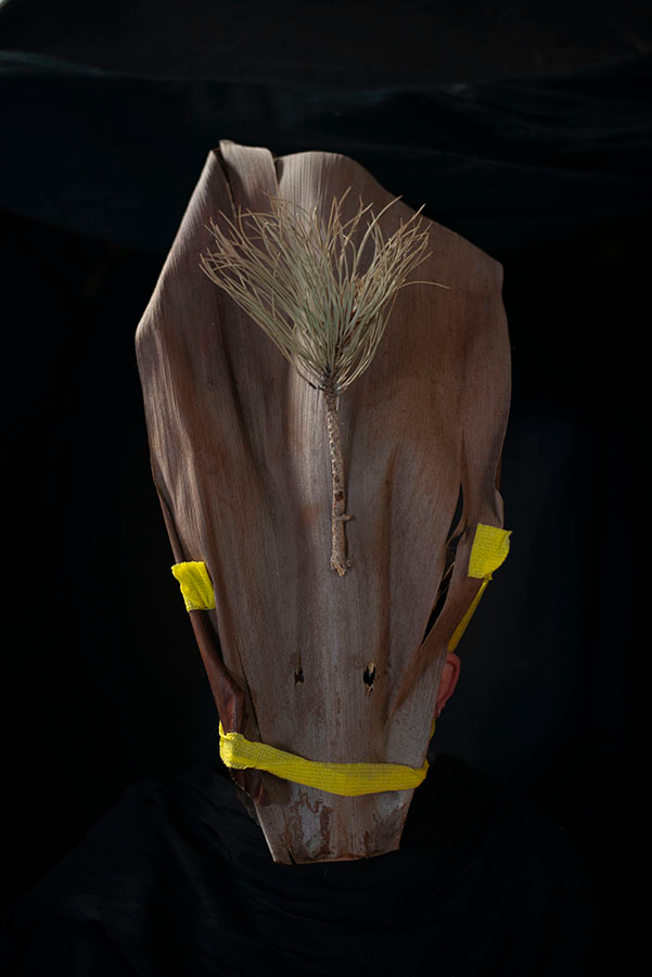 A natural material form with accents of yellow tape on a black background.