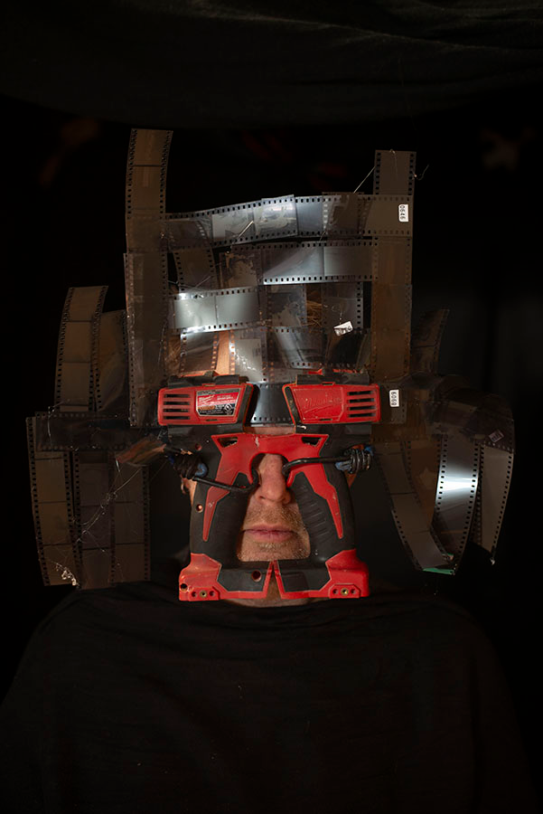 A mask that looks a bit like a superhero, consisting of drill parts and 35 mm negatives.