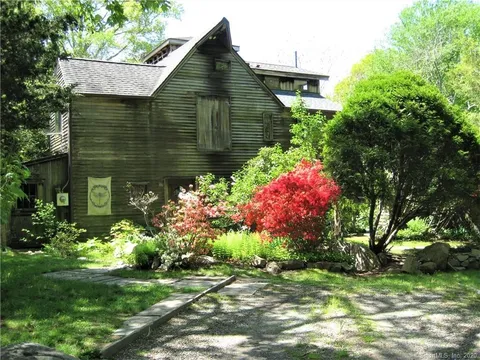 exterior of a dark wood shingled house with landscaping in the foreground.