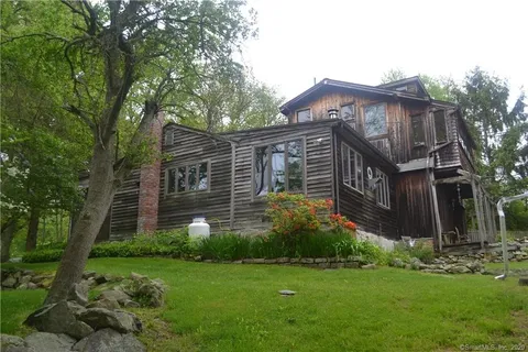 Exterior of a dark wood shingled home with a green lawn in the foreground